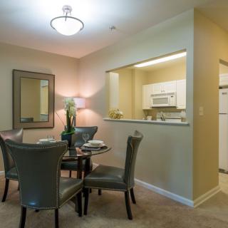 A cozy dining area with a round table and four chairs, adjacent to a small open kitchen.