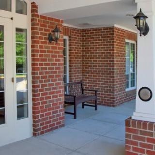 A cozy porch with brick walls, a bench, and decorative lanterns.