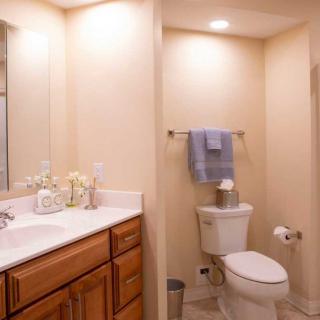 A clean and organized bathroom with a sink, mirror, and toilet featuring neutral tones and simple decor.