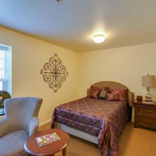 A cozy bedroom with a bed, armchair, and decorative wall art.