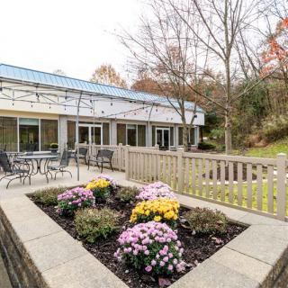 A scenic view of an outdoor patio area with flower beds and seating arrangements, surrounded by greenery.