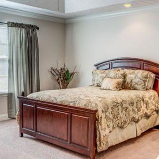 A cozy and well-decorated bedroom with a wooden bed frame and patterned bedding.
