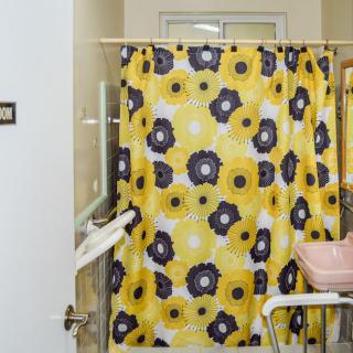 A bathroom with a vibrant yellow shower curtain featuring a floral pattern.