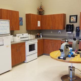 A well-equipped kitchen area in a laboratory setting, featuring cabinets and a microscope on the table.