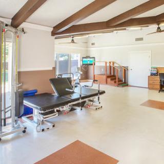 A spacious and well-equipped physical therapy clinic featuring treatment tables and exercise areas.