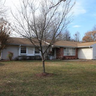 A suburban ranch-style house with a tree in the front yard.