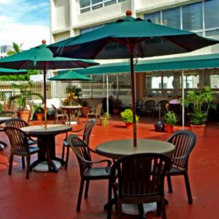 A sunny outdoor patio with tables, chairs, and umbrellas.