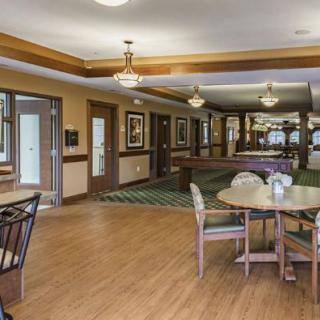 A cozy dining area with tables and chairs, featuring elegant lighting and decorative wall art.