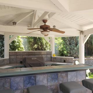 A cozy outdoor patio bar area with seating and a ceiling fan.