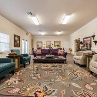A cozy living room featuring a variety of seating options, a patterned carpet, and warm lighting.