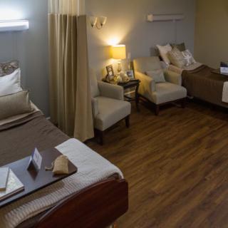A cozy hospital room with two beds and comfortable seating.