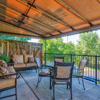 An inviting outdoor patio area with a canopy, featuring comfortable seating and a table for relaxation.