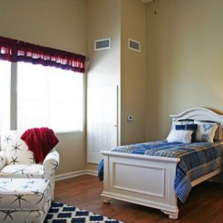 A cozy bedroom with a single bed and an armchair next to a window.