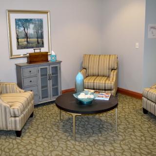 A cozy living room setting with striped chairs, a wooden table, and decorative items.