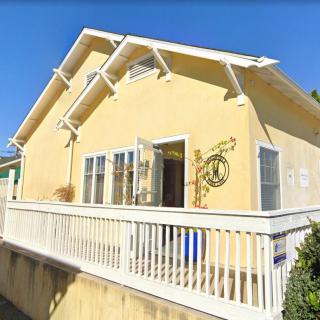 A yellow house with a balcony and white railing on a sunny day.