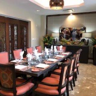 A beautifully set dining room with elegant decor and a long table surrounded by cushioned chairs.