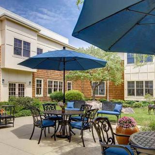 A cozy patio area with tables and chairs under blue umbrellas in a sunny courtyard.