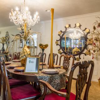 A beautifully decorated dining room with an elegant chandelier and ornate mirror.