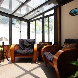 A bright sunroom with wooden chairs and abundant natural light streaming through the glass roof.