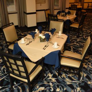 An elegantly set dining table in a restaurant with beige and blue accents.