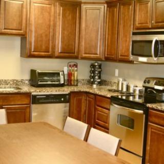 A modern kitchen with wooden cabinets, stainless steel appliances, and a countertop dining area.