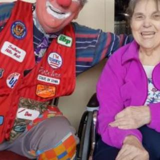 A clown sharing a joyful moment with an elderly woman.