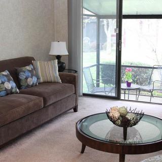 Cozy living room with a sofa and coffee table next to a sliding door leading to a balcony.