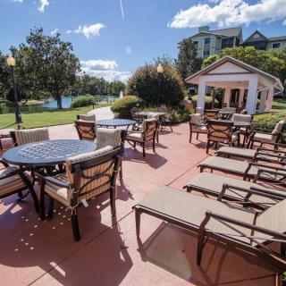 A sunny outdoor patio with tables, chairs, and a small pavilion in the background.