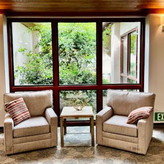 A cozy seating area with two chairs and a view of lush greenery outside.