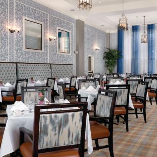 An elegant dining area with neatly arranged tables and chairs, adorned with white tablecloths and sophisticated decor.