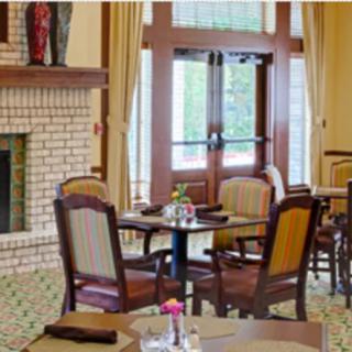 A cozy restaurant interior with neatly arranged tables and chairs next to a fireplace.