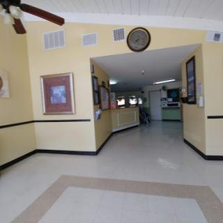 A spacious lobby featuring yellow walls adorned with artwork and a ceiling fan.