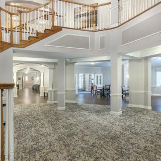 Spacious foyer with an elegant staircase and carpeted flooring.
