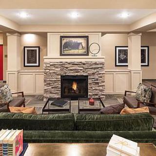 A cozy living room featuring a stone fireplace, comfortable seating, and tasteful artwork.