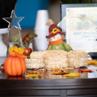 A festive autumn display featuring decorative pumpkins, a scarecrow, and delicious treats.