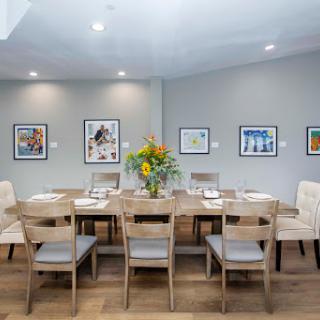 A beautifully arranged dining room featuring modern furniture, vibrant floral arrangements, and art displayed on the walls.