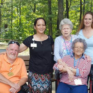 A group of people posing together in a park setting with trees in the background.
