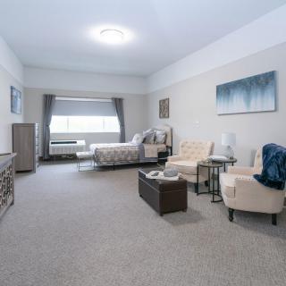 A spacious and modern bedroom featuring elegant furniture and a large window.