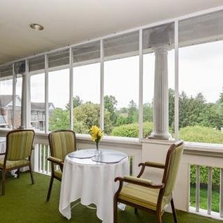 A cozy balcony with a small table and chairs overlooking a lush, green landscape.
