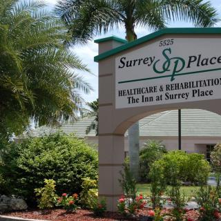 Entrance sign of Surrey Place, surrounded by palm trees and landscaped greenery.