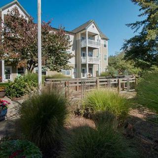 An apartment building surrounded by well-maintained landscaping on a sunny day.