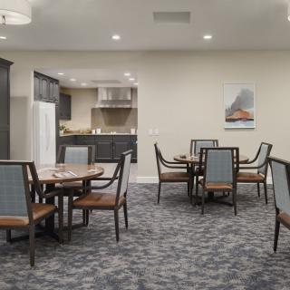 A well-appointed dining area with round tables and chairs, adjacent to a kitchen space.