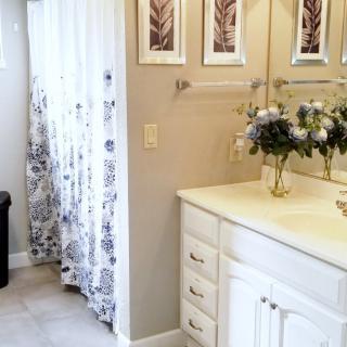 A well-decorated bathroom with a vanity, floral arrangements, and a shower curtain.