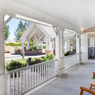 A spacious outdoor porch with seating and a view of a well-maintained garden.