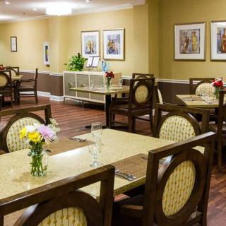 A well-decorated dining room with neatly arranged tables and chairs, adorned with flowers and paintings on the walls.