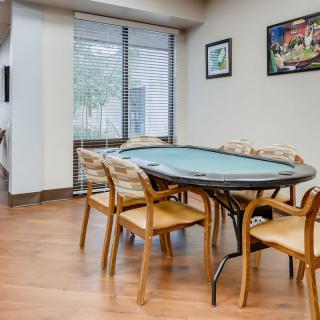 A room with a poker table and chairs, featuring hardwood floors and artwork on the walls.