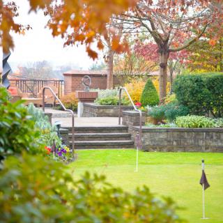 A peaceful garden scene with colorful autumn leaves and neatly manicured lawns.