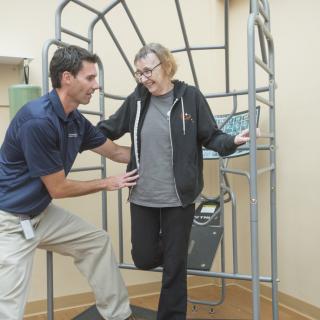 A therapist assists a person with balance training using specialized equipment.