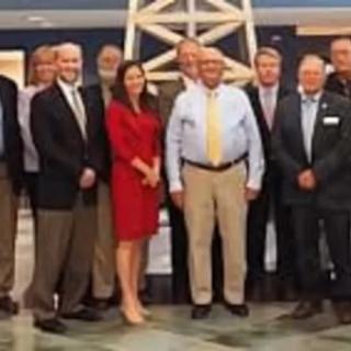 A group of individuals dressed in formal attire posing for a photo indoors.