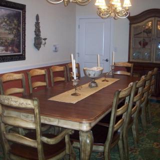 A dining room with a long wooden table and chairs, adorned with candles and a chandelier overhead.